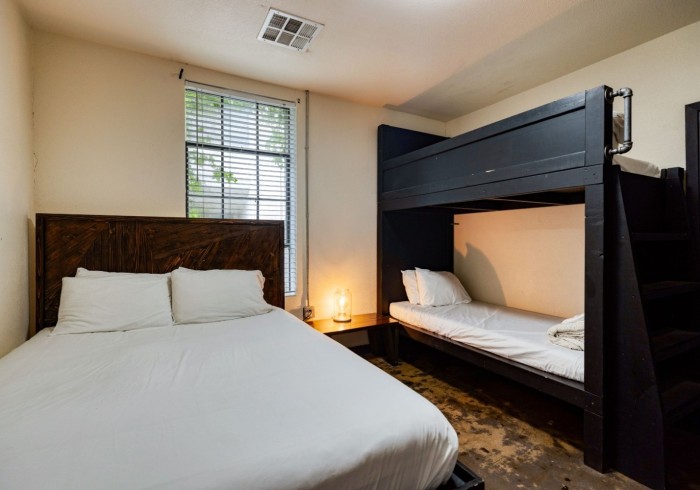 Brazos Suite with queen bed and bunk bed, natural light and warm lamps
