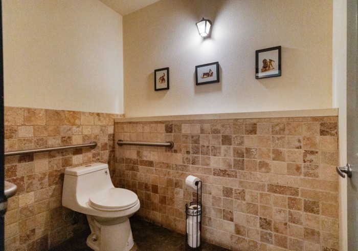 Bathroom with travertine wainscoting, lantern light fixture, and framed art