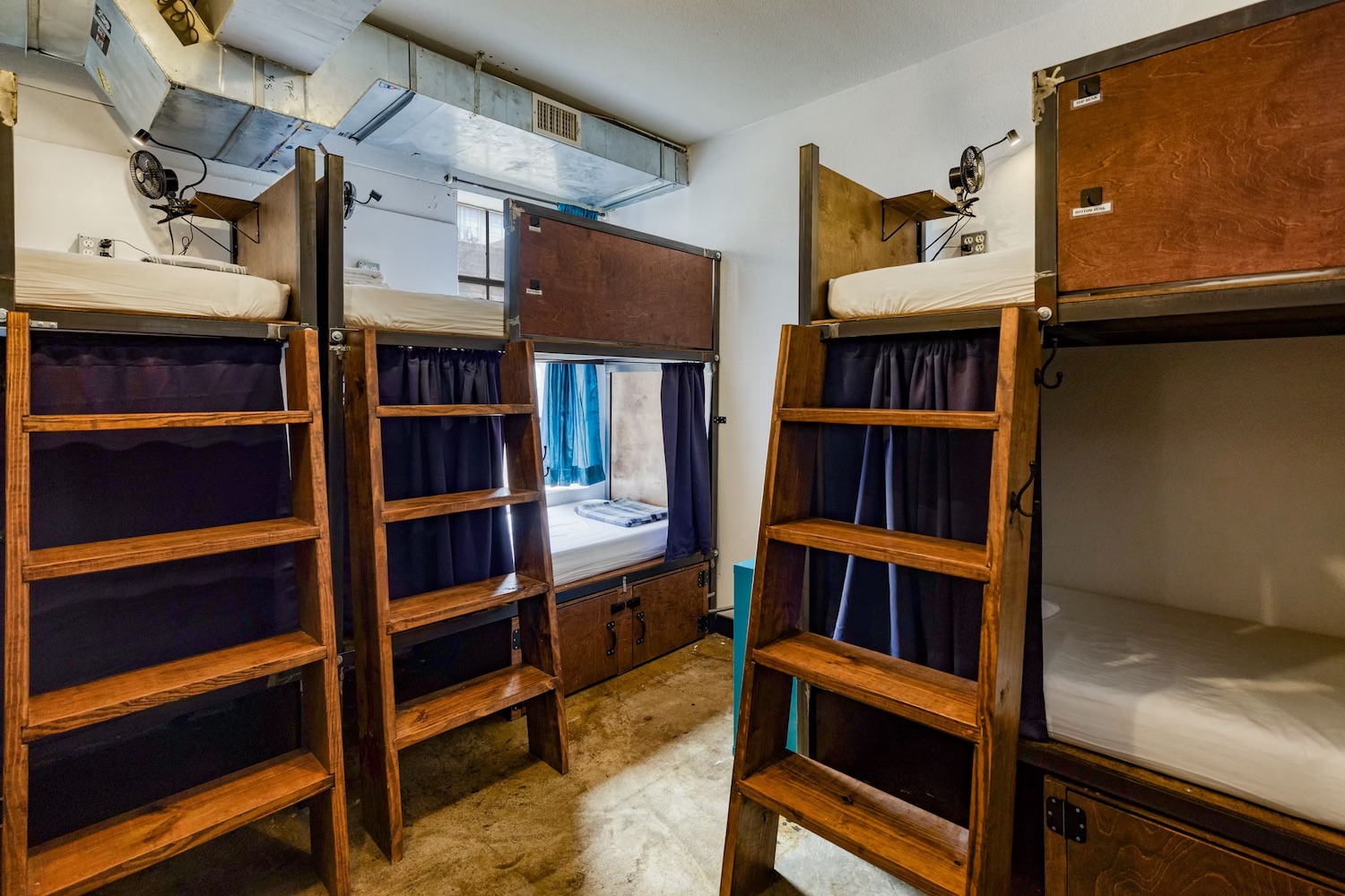 Single bunk pod with blue privacy screen and pillows